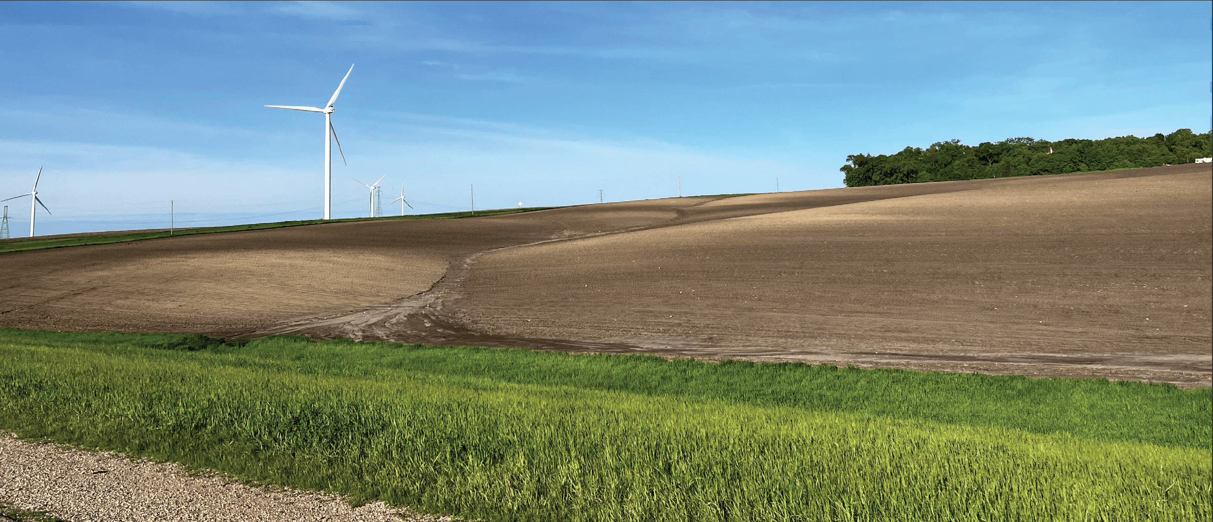 A wind turbine in an open field on a sunny day.