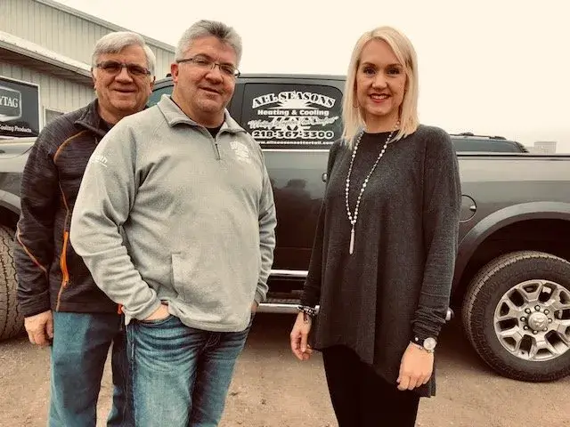 Picture of three smiling in front of truck