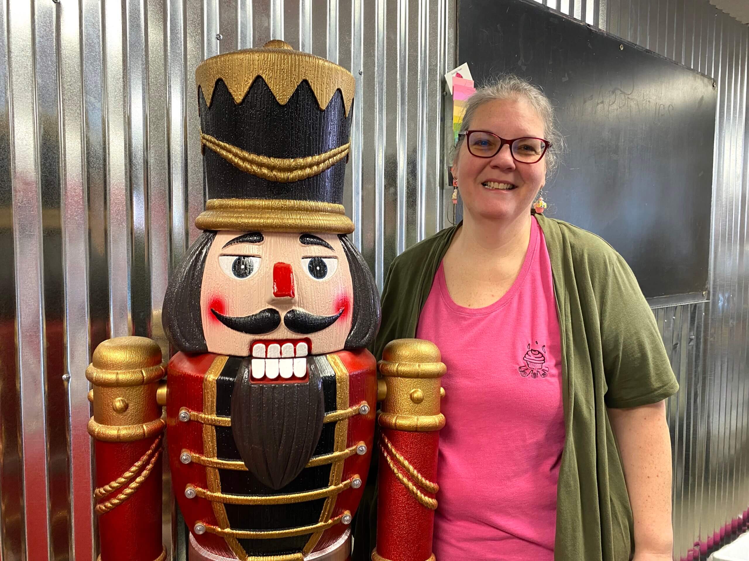 Amy Camp, owner of Nutcracker Cafe & Bakery, stands next to a large nutcracker and smiles.