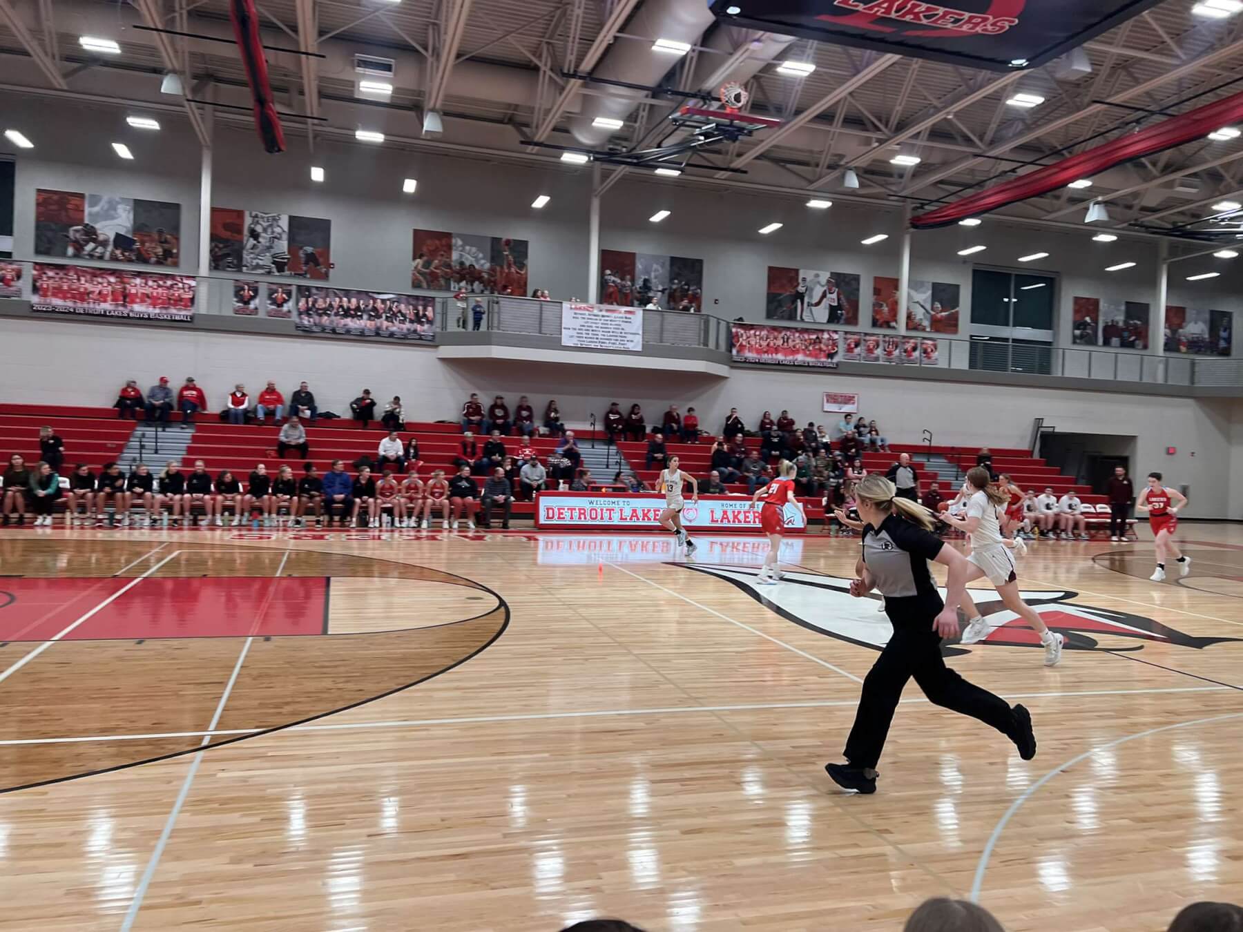 Referee running down a basketball court during a basketball game.
