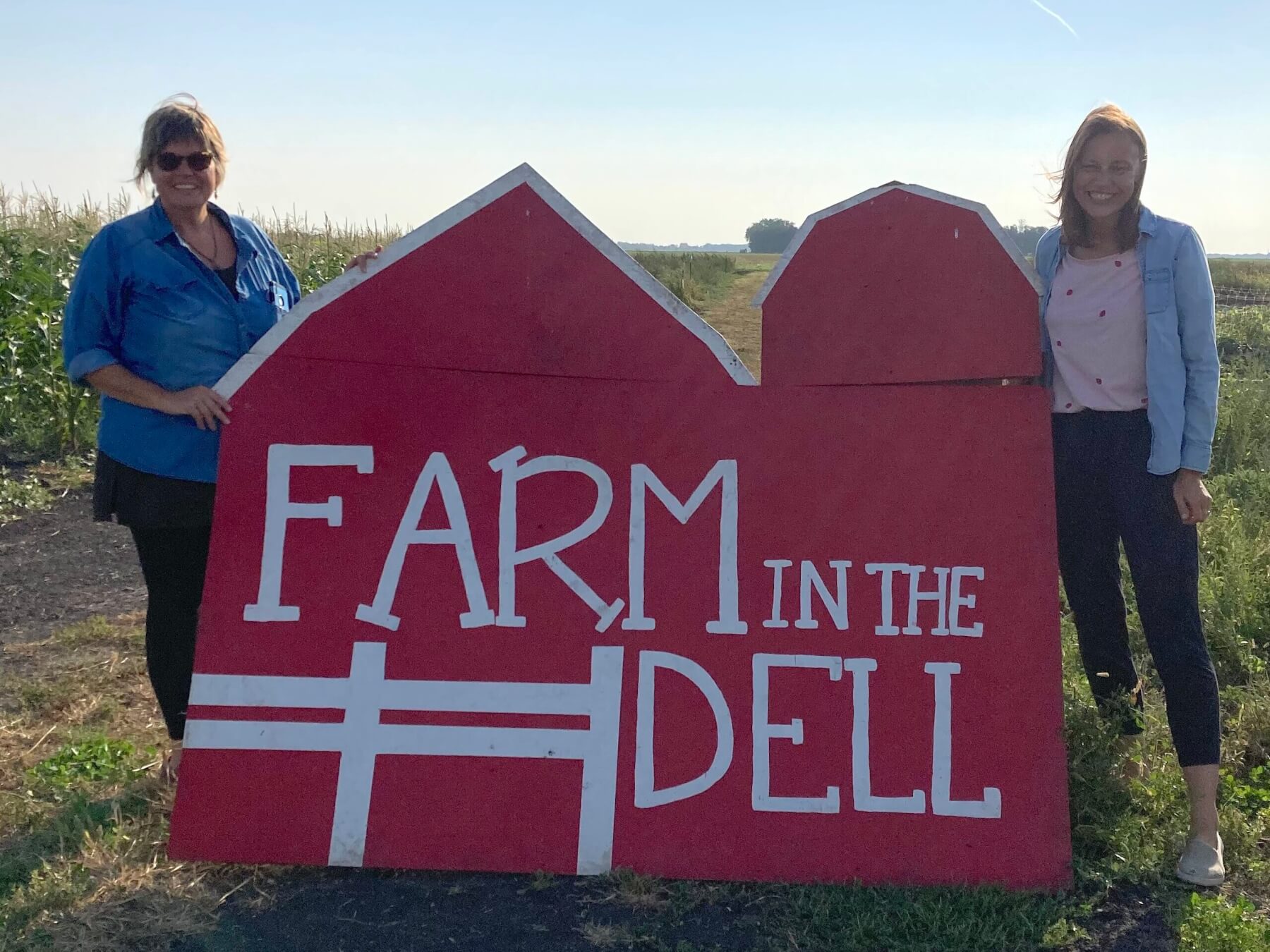 Kate and Anne hold Farm in the Dell sign