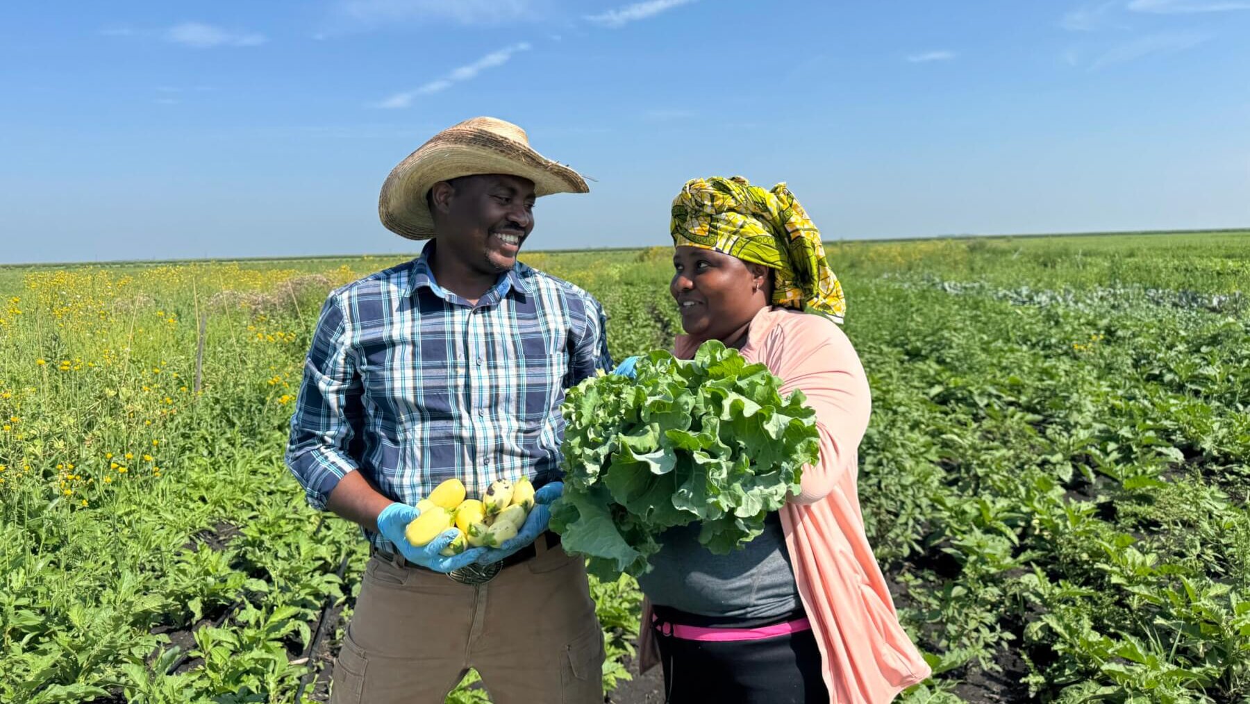 Caliton and Honoree on the farm holding vegetables.
