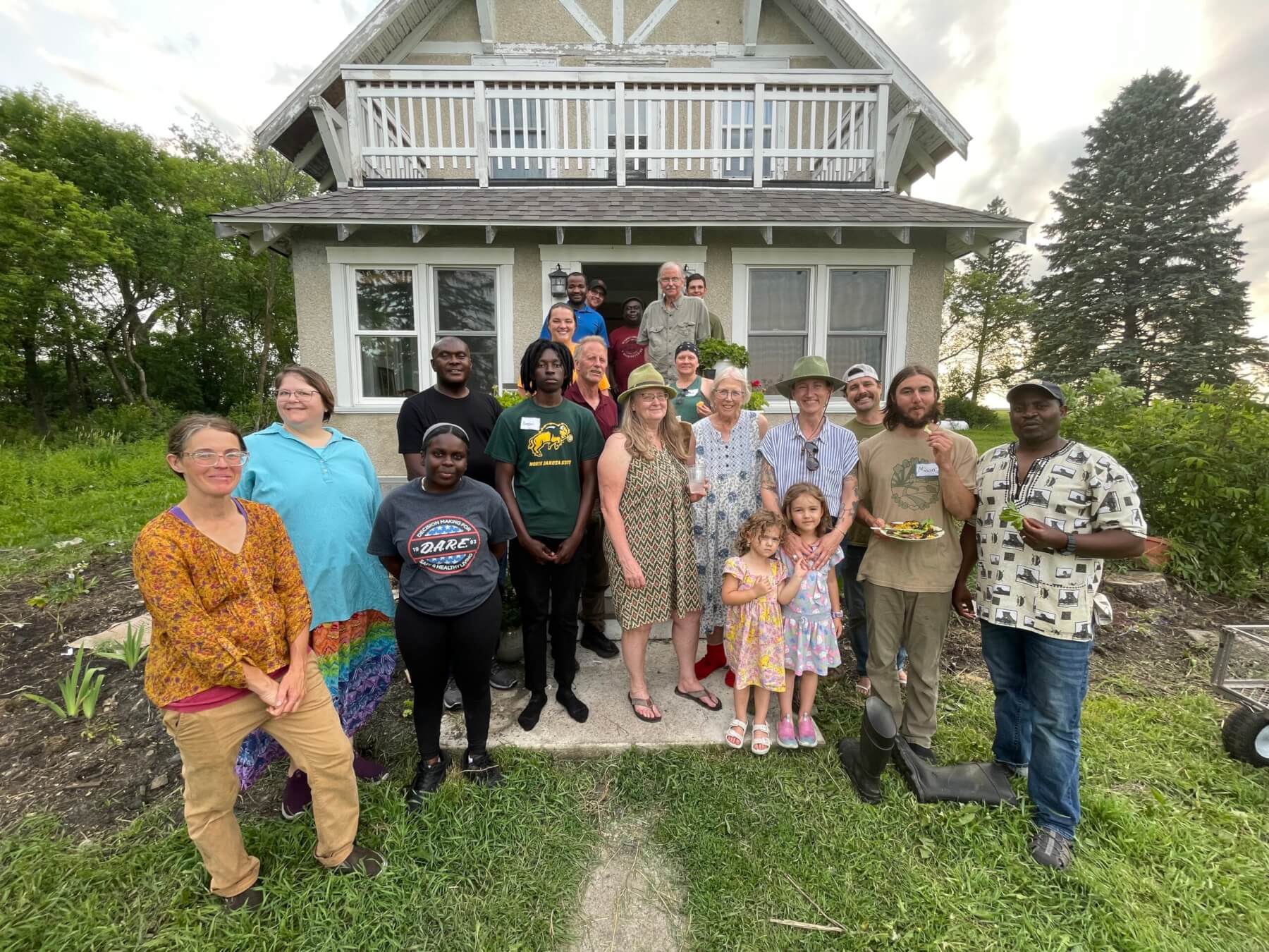 A group of people standing outside a house smiling at a local food event.