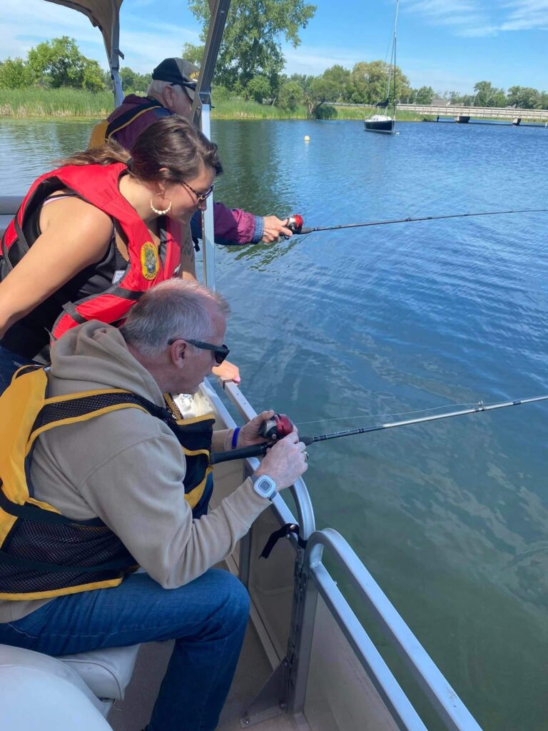 Caretaker and older man fishing off of boat.