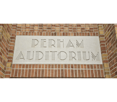 Brick building facade with a light stone panel reading “Perham Auditorium” in engraved letters.