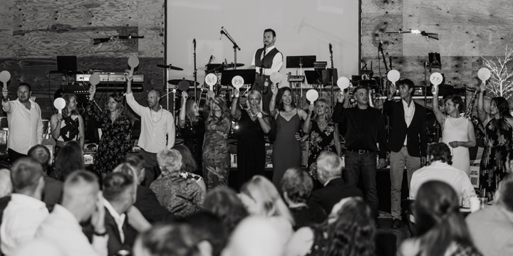 Black-and-white photo of people on stage holding paddles during a live auction event.