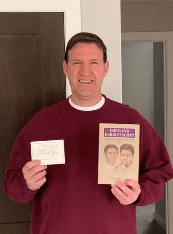 smiling man holding a book and thank you note
