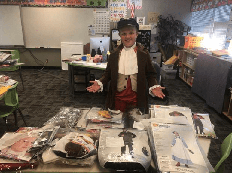 child presenting a table of costumes while in costume