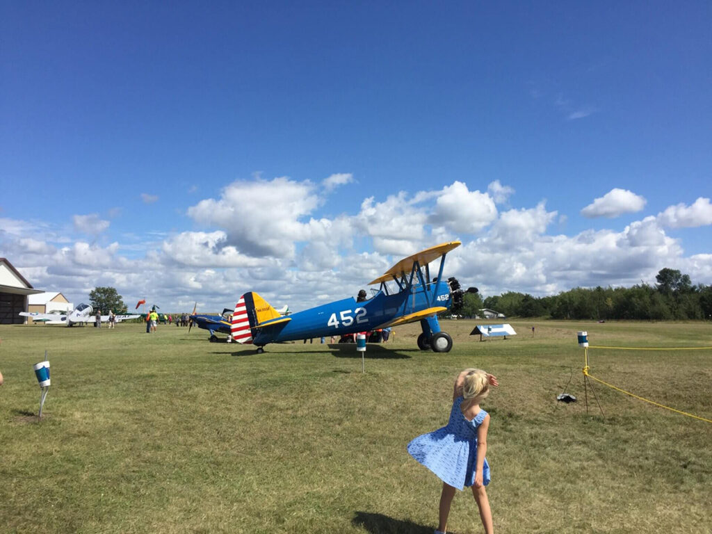 little girl looking at an airplane on a field