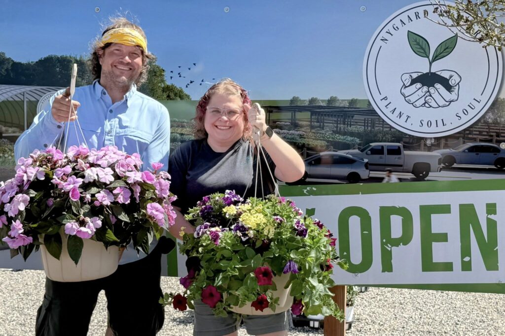 A man and women hold hanging baskets of flowers, which were gifts from the Clay County Early Chilhood Fund to providers.