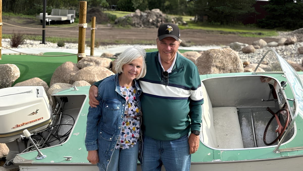 Morrie and Ruthie Lanning stand together smiling on a sunny day. They are outside. Morries arm is around Ruthie.
